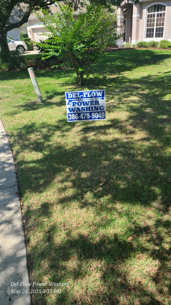 del-flow power washing yard sign displayed on a grassy area near a house indicating their power washing services available