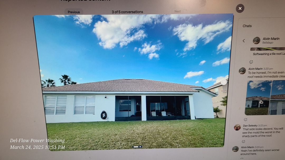 del-flow power washing cleaning a residential house exterior with a focus on roof and siding areas under clear skies