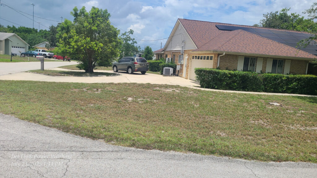 del-flow power washing working on a residential area with a driveway and grass lawn visible in the photo