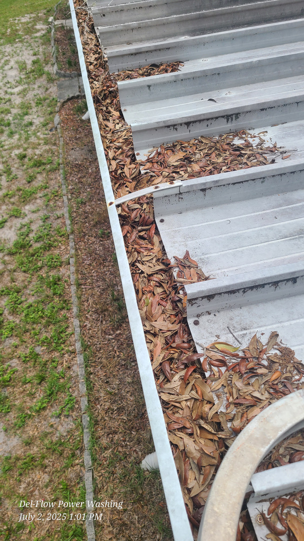 gutters being cleaned with leaves and debris accumulated along the edge of the roof and surrounding area